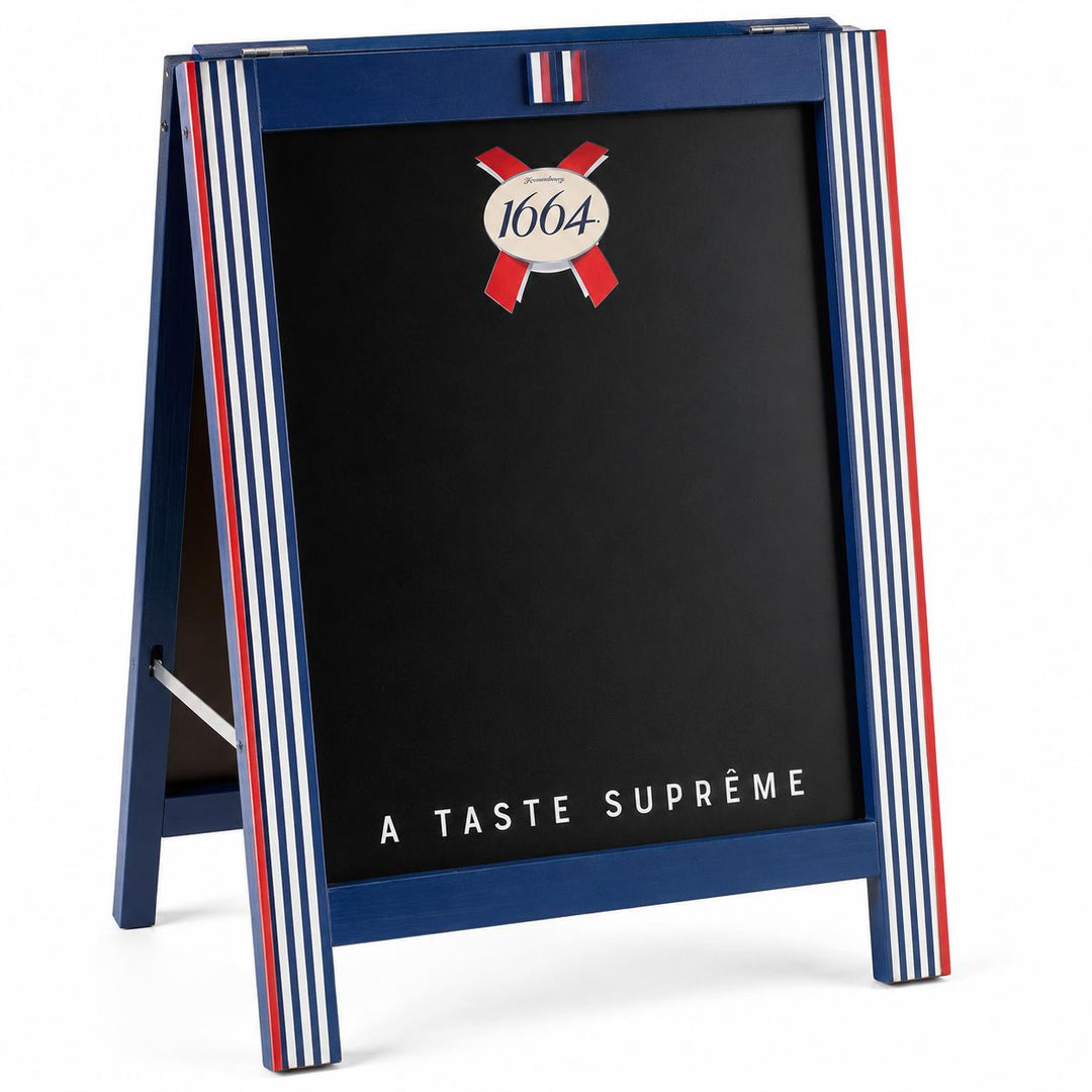 A blue A-frame chalkboard sign with red and white vertical stripes on the sides, featuring the 1664 logo and the text 'A TASTE SUPRØME' on a black board, photographed on a white background.