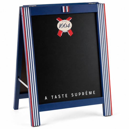 A blue A-frame chalkboard sign with red and white vertical stripes on the sides, featuring the 1664 logo and the text 'A TASTE SUPRØME' on a black board, photographed on a white background.